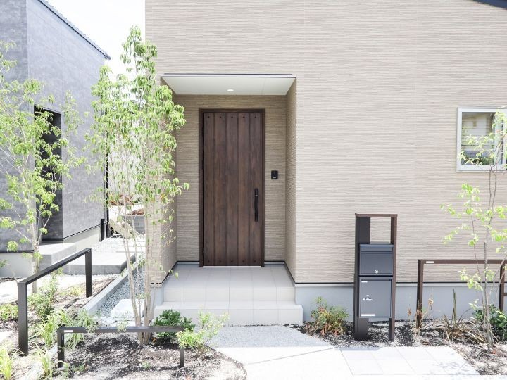 ベージュの外壁に焦げ茶色の玄関ドアがアクセントとなり、温かみのある落ち着いた外観を演出。